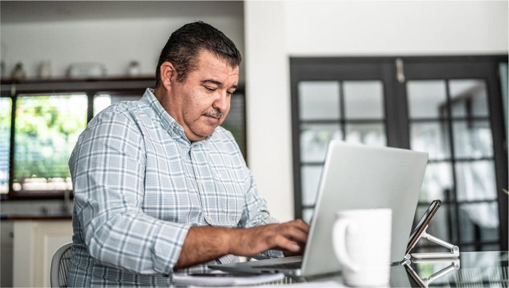 Image of an older man sitting at home while using his laptop